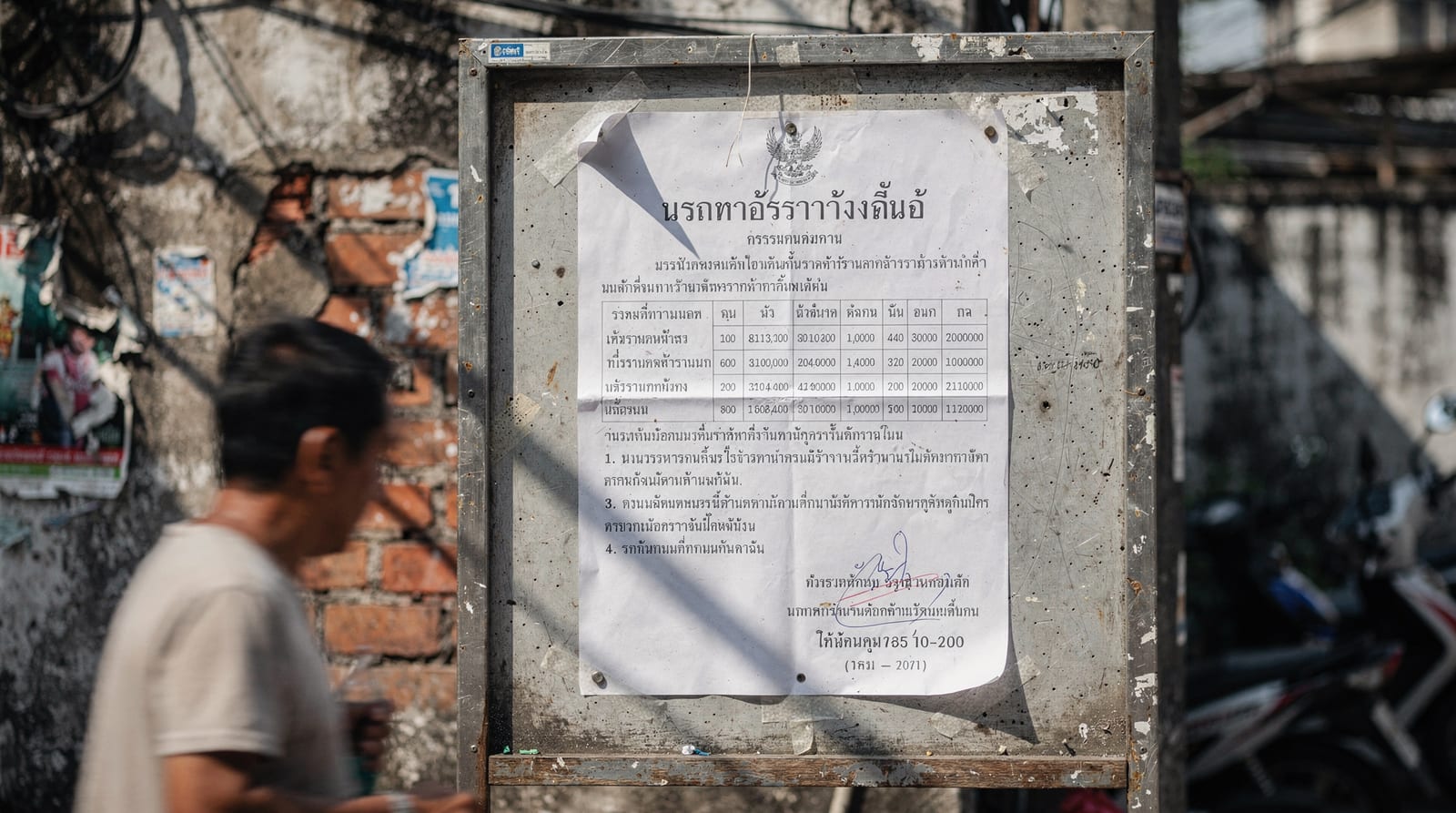 An official Thai government minimum-wage notice posted on a public noticeboard, a passer-by blurred in motion.